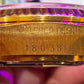 Gold Rolex watch case with 'Registered Design' and '18038' engraving held by a hand.